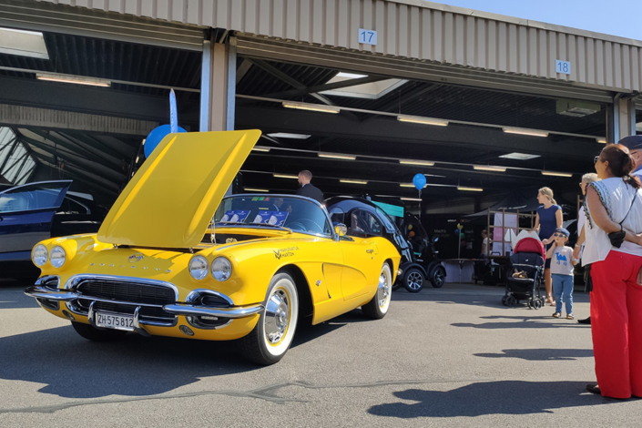 emobilitaet_zug21_2 Eine gelbe Corvette Jahrgang 1962 steht mit offener Motorenhaube vor einer Halle.
