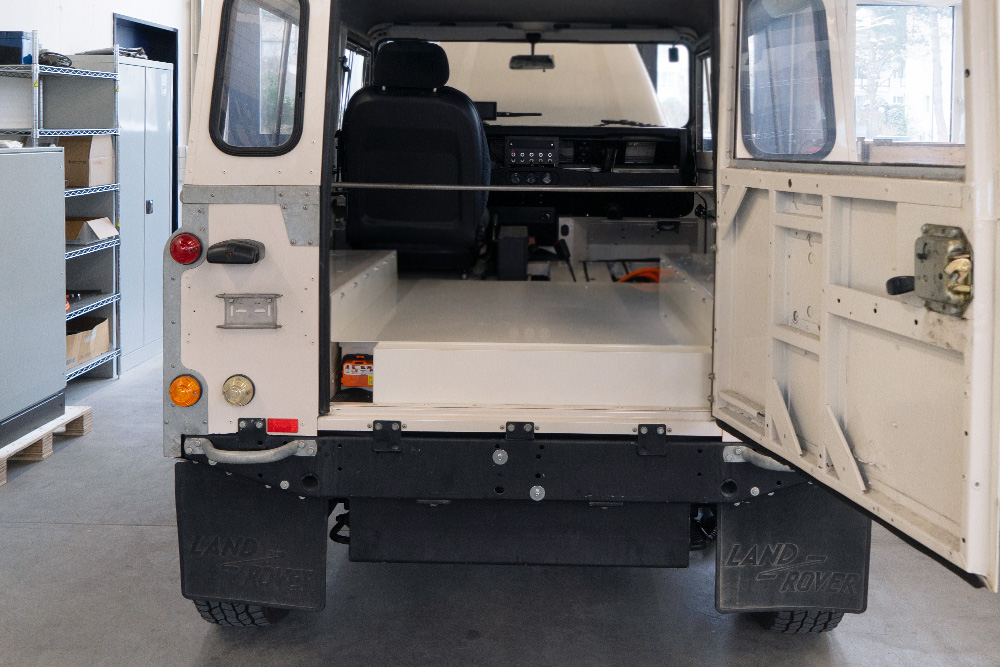 dEfender_manufakturmarton_galerie_04574 Das Heck eines Land Rover Defenders, mit Sicht auf die Ladefläche. Die Batteriekiste in Wagenfarbe findet auf der Ladefläche platz.