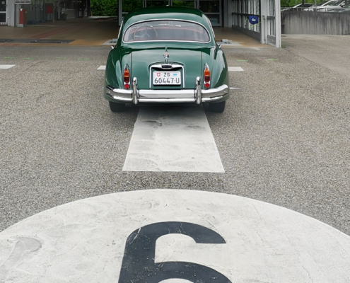 Jaguar XK 150 vor Strassenverkehrsamt Ein grüner Jaguar XK 150 steht auf einer Prüfbahn des Strassenverkehrsamtes Zug. Ansicht von Hinten auf das Auto. Man erkennt die Bahnnummer 6 im Bild unten, etwas angeschnitten.