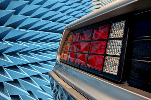 EMV Testlabor DeLorean Ein Teil des Hecks des DeLoreans in einer Prüfhalle für elektromagnetische Immunität. Im Hintergrund die Wand der Halle, an der blaue Pyramidenabsorber angebracht sind.