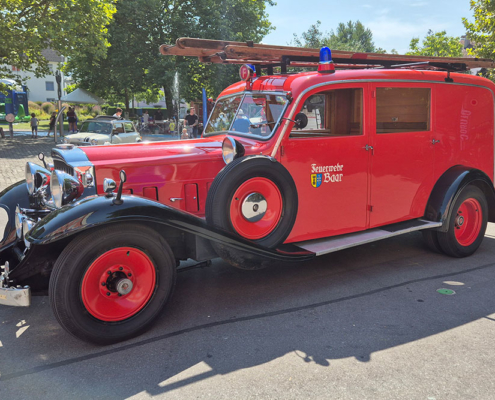 20240901_134617_blog Ein zum Feuerwehrauto umgebauter Packard. Vorne Nebelhörner, oben Blaulicht und eine Leiter aus Holz.