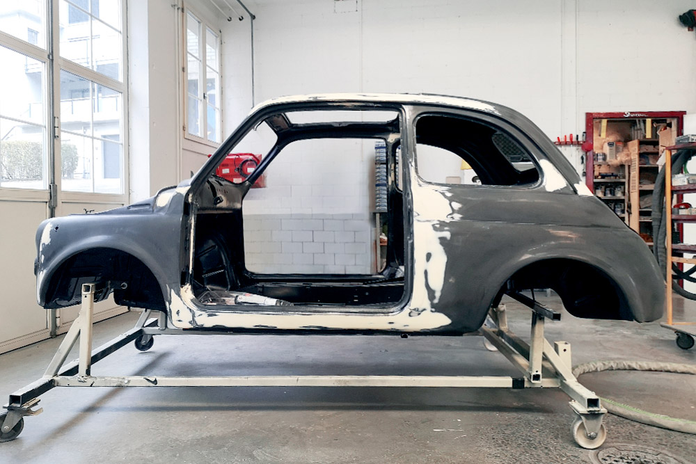 Die Karosserie des Fiat 500, mehrheitlich schwarz von der KTL-Lackierung. Einzelne Stellen sind heller, dort wurden unebenheiten aufgefüllt zur Vorbereitung für die Lackierung