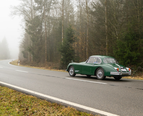 Jaguar auf nebliger Strasse Elektrischer Jaguar XK150 fährt auf Landstrasse im Nebel