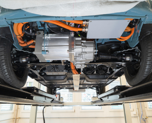 DSC09092_manufakturmarton_webgallerie Blick auf den Unterboden eines Fahrzeugs. Man sieht Kabel, einen Elektromotor mit Getriebe/Differential.